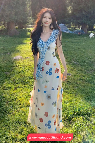 Woman in a floral dress standing in a grassy field with trees in the background.