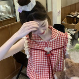 Person wearing a red and white checkered outfit with a bow, sitting indoors.