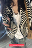 Person wearing a black and white striped cardigan with a beige bag, blurred background
