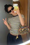 Person taking a mirror selfie wearing a striped shirt and leopard print bag.