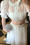 Person wearing a white outfit with a decorative clutch in an indoor setting