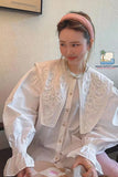 Woman wearing a white embroidered blouse with a pink headband indoors.