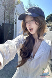 Woman wearing a white blouse and blue cap outdoors on a sunny day