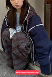 Person wearing a blue jacket with plaid lining sitting on a step.