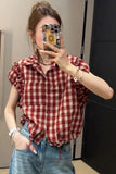 Person wearing a red and white checkered shirt and blue jeans, taking a mirror selfie.