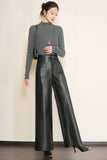 A woman modeling a dark gray long-sleeve mock neck top and black wide-leg faux leather pants, styled with a silver pendant necklace and black pointed-toe heels against a beige wall.