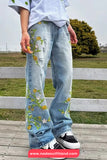 Person wearing light blue jeans with floral embroidery standing outdoors.