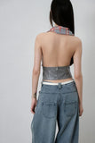 Person wearing a metallic halter top and jeans on a plain background