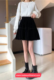 Person wearing a white sweater and black skirt standing in a modern interior setting.