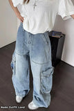Person wearing a white oversized t-shirt and blue baggy jeans indoors.
