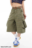 Person wearing plaid shorts with a belt and blue sneakers on a white background