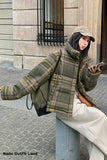 Person wearing a plaid jacket sitting on a bench with a phone in hand.