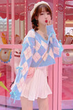 Woman wearing a pastel argyle cardigan and skirt in front of a pink candy machine.