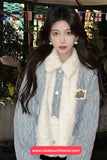 Woman wearing a light blue jacket with a white fur scarf in an indoor setting.