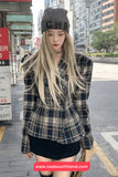 Woman wearing a plaid jacket and beanie on a city street, with a visible brand watermark.
