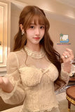 Woman wearing a beige lace top in an indoor setting with 'Nada Outfit Land' logo.