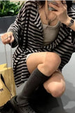 Person wearing a black and white striped sweater sitting on a bench.