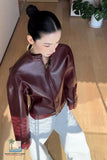 Person wearing a maroon leather jacket indoors with a plant in the background