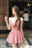 Woman in a pink checkered dress standing on a street with a blurred background