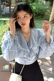 Woman wearing a light blue blouse with ruffled sleeves in an outdoor setting