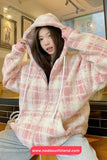 Person wearing a pink and white checkered hoodie with a blurred indoor background