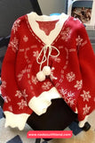 Red sweater with white snowflake patterns and pom-poms on a chair.