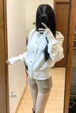 Person wearing a white jacket and light-colored shorts in front of a mirror.
