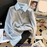 Gray sweater vest over a striped shirt on a chair with a blurred background