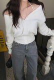 Person wearing a white off-shoulder sweater and gray jeans indoors.