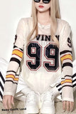 Person wearing a white sweater with black and yellow stripes and 'VINI' text, sitting on a striped chair.
