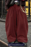 Person wearing maroon corduroy pants with a blurred background
