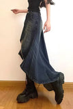 Person wearing a long blue denim skirt and black platform boots on a plain background