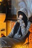 Person wearing a leopard print hoodie sitting on a chair with a warm glow.