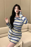 Woman wearing a striped dress sitting on a beige couch.