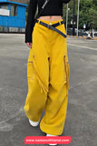 Person wearing yellow cargo pants on a street with a blue building in the background