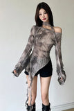 A woman modeling a sheer, asymmetrical long-sleeve top with a gray and black tie-dye pattern, paired with black shorts and black boots, against a plain light gray wall.