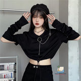 Person wearing a black outfit with a crop top and pants, posing indoors.