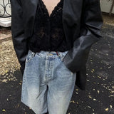 Person wearing a black jacket, black top, and blue jeans on a street.