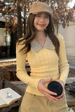 Woman in yellow sweater and beige cap holding a coffee cup outdoors.