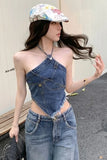 Woman wearing a denim outfit with a colorful cap, standing outdoors.
