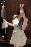 Woman taking a mirror selfie wearing a white dress in a fitting room.