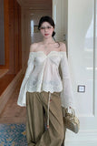 Woman wearing a white off-shoulder top and beige pants in a hallway.