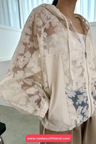 Person wearing a beige lace-trimmed outfit with a blurred background