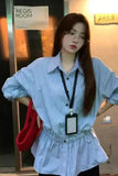 Woman wearing a striped shirt with a red bag and lanyard, standing in front of a door labeled 'Aegis Room'.