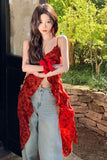 Woman wearing a red floral top and light blue jeans standing outdoors.