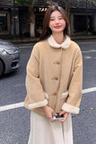 Woman wearing a beige coat with white fur trim on a street.