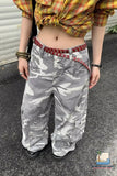 Person wearing a plaid shirt and camouflage pants with a red belt.