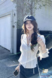 Woman wearing a white blouse and black cap outdoors with a blurred background