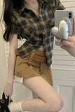 Person wearing a plaid shirt and beige shorts, taking a mirror selfie.