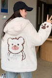 Person wearing a white fluffy jacket with a bear design and paw print sleeves.